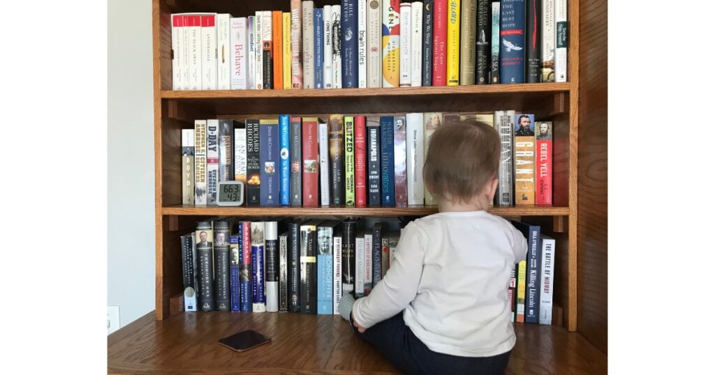 Toddler in front of two shelves of library books