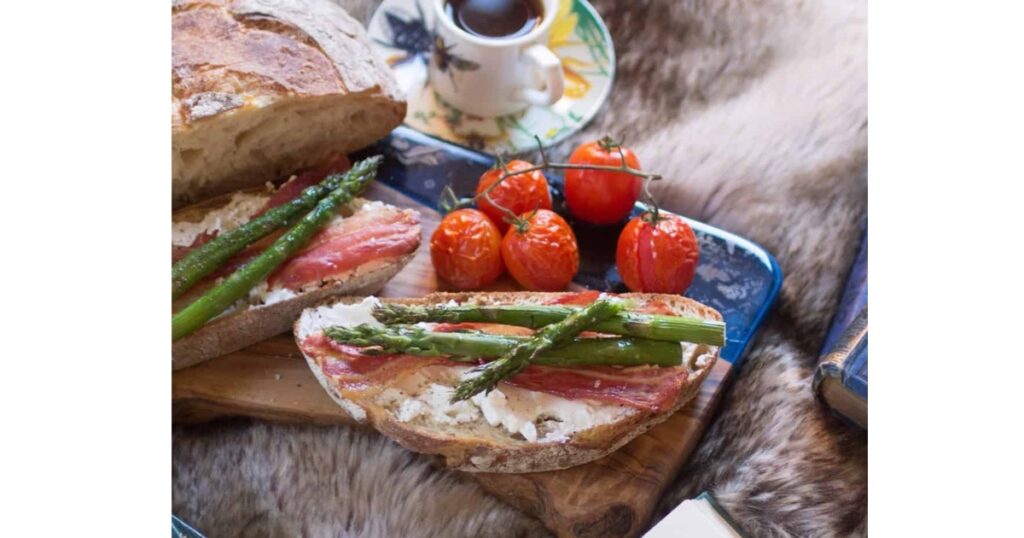Toast with cream cheese, asparagus, bacon and tomatoes. Background of ingredients within dish.