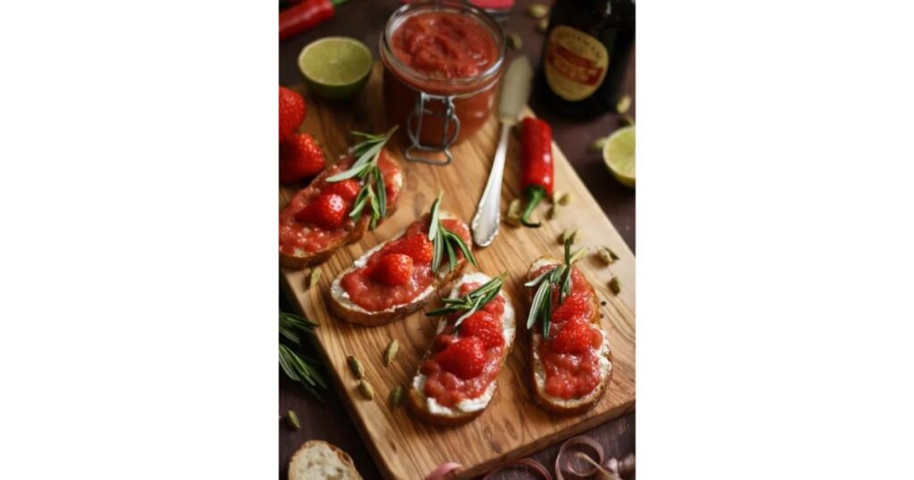 Four pieces of crostini with red chutney on top and in left hand corner.