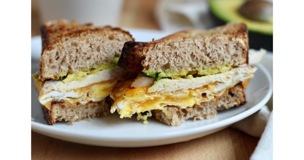 Turkey, egg and avocado on a slice of bread on a white plate.