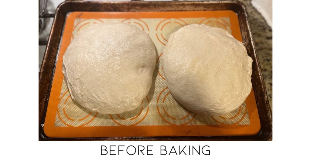 Two loaves of sourdough bread on a cream and orange silicone baking sheet. Words 'before baking' at bottom of photo.