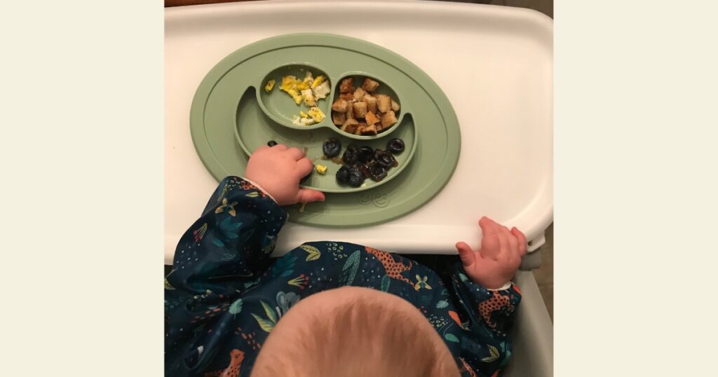 Child eating breakfast off of green plate.