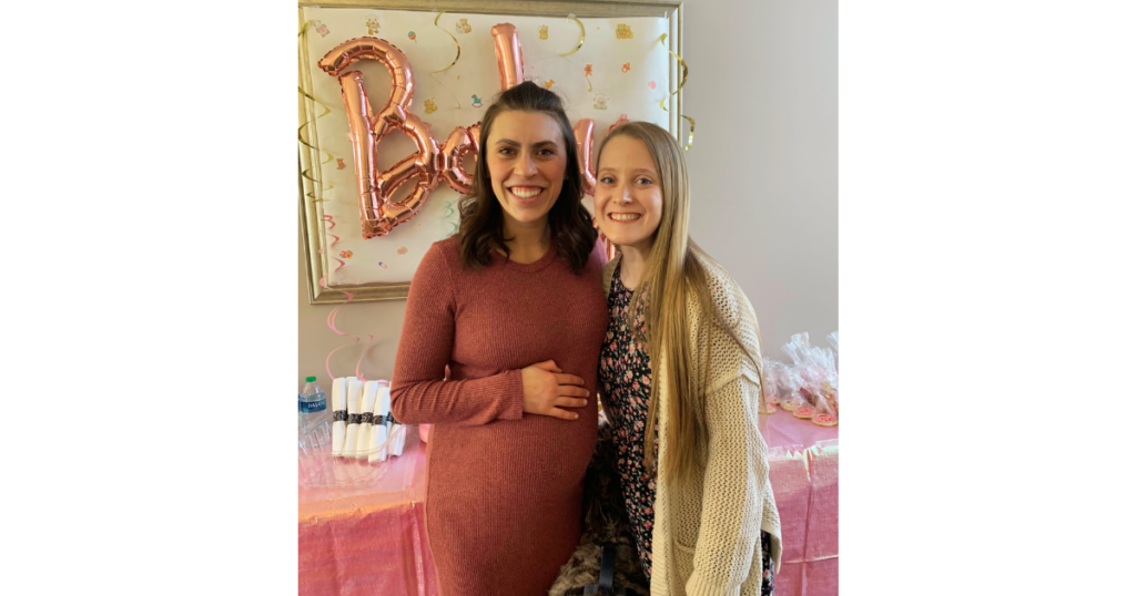 Pink baby sign behind two women