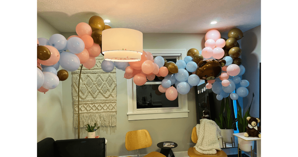 Balloon arch with blue, pink and brown balloons. Two chars and two lamps.