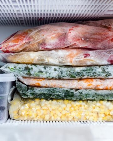 Freezer with 6 bags stacked with vegetables.