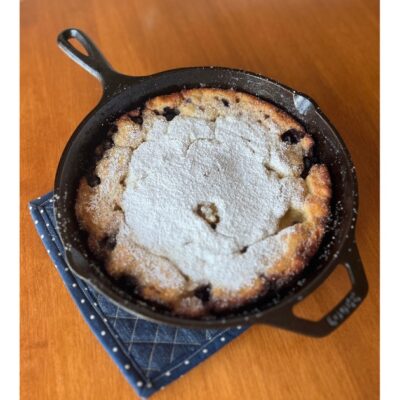 sourdough dutch baby in cast iron skillet on blue pot holder.