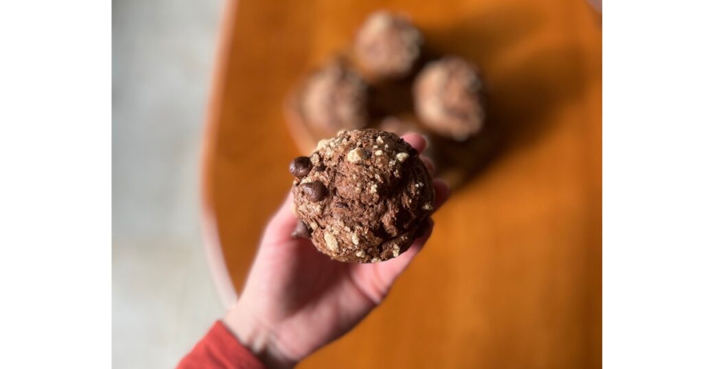 holding a double chocolate sourdough muffin with turinado sugar