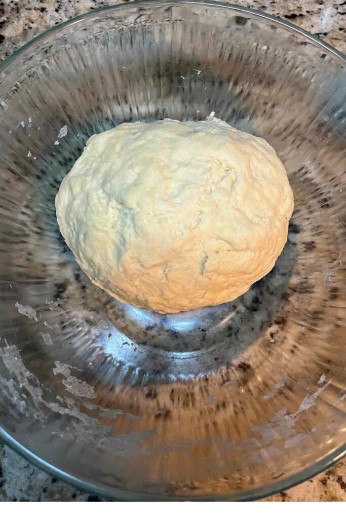 knead sourdough hawaiian roll dough in a glass bowl.
