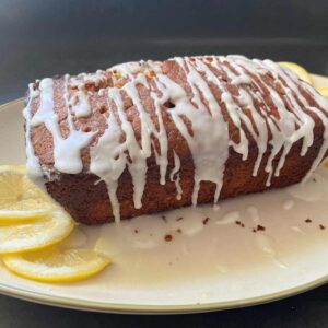 sourdough lemon poppyseed loaf with lemon glaze and lemon slices in corner of plate.