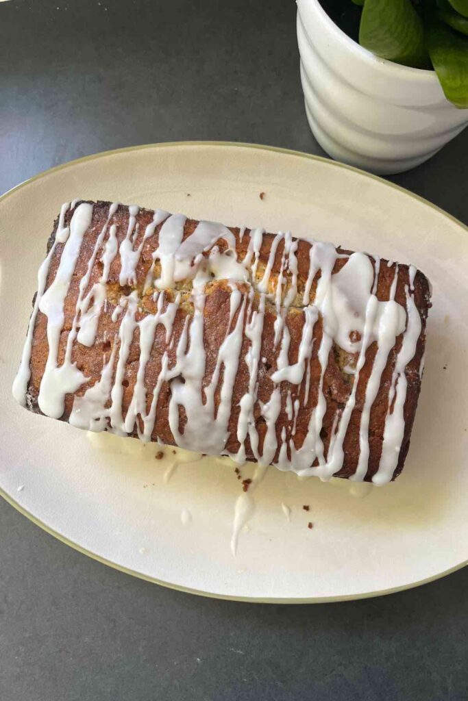 sourdough lemon poppyseed loaf on pan with lemon drizzle on top.