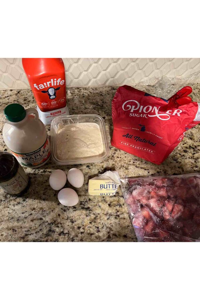 ingredients for strawberry sourdough dutch baby on granite countertop and white backsplash.