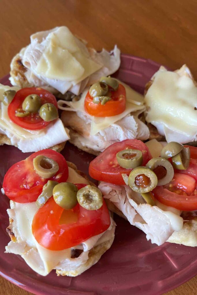 sandwich with tomato, lunch meat, cheese and green olives.