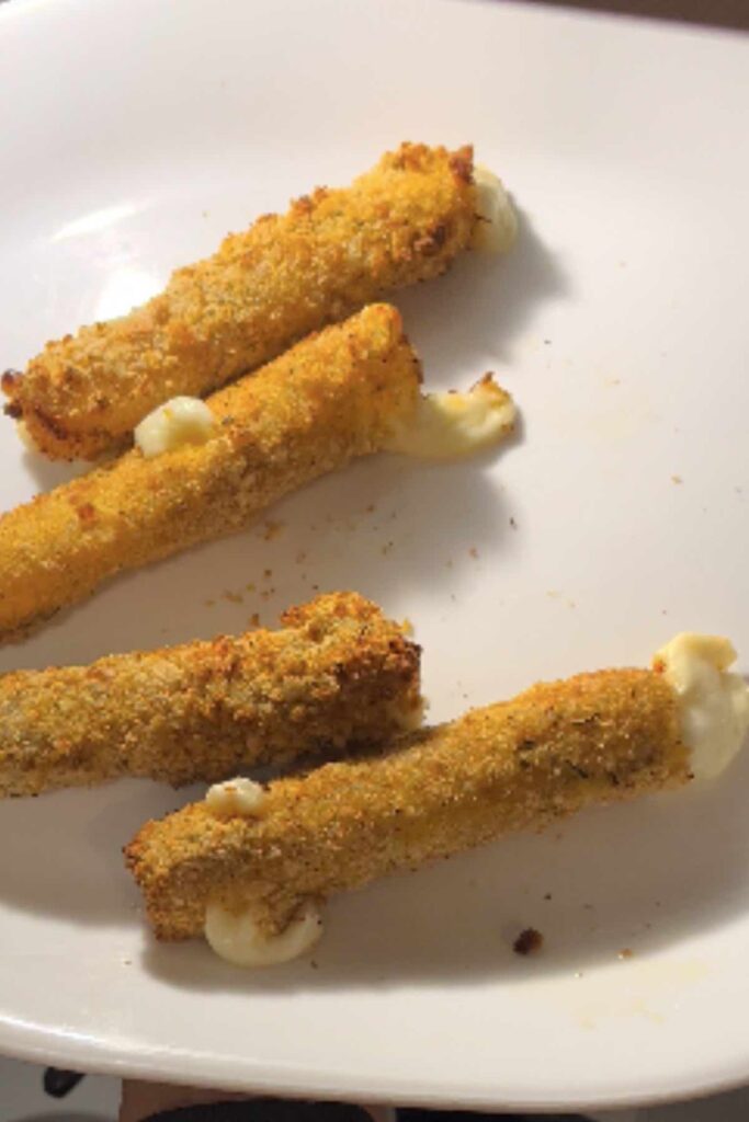 four mozzarella sticks on a white plate.