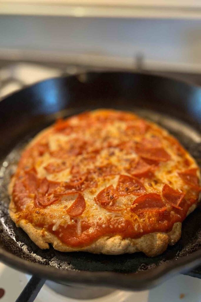 whole wheat sourdough pizza in cast iron skillet on stove.