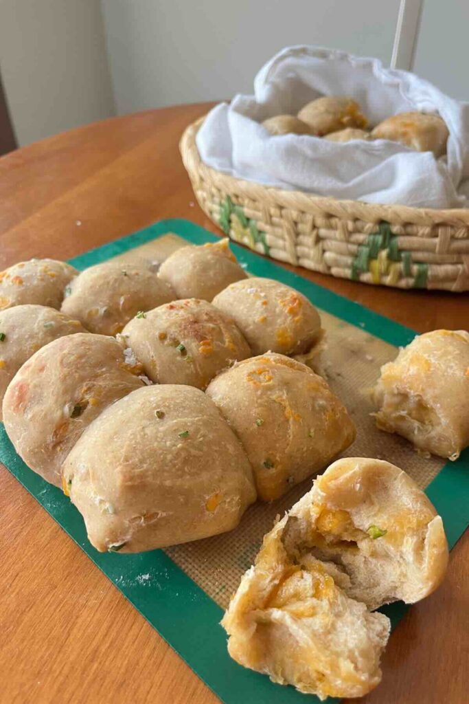 garlic scape cheddar rolls with some on tray and some in bread basket.