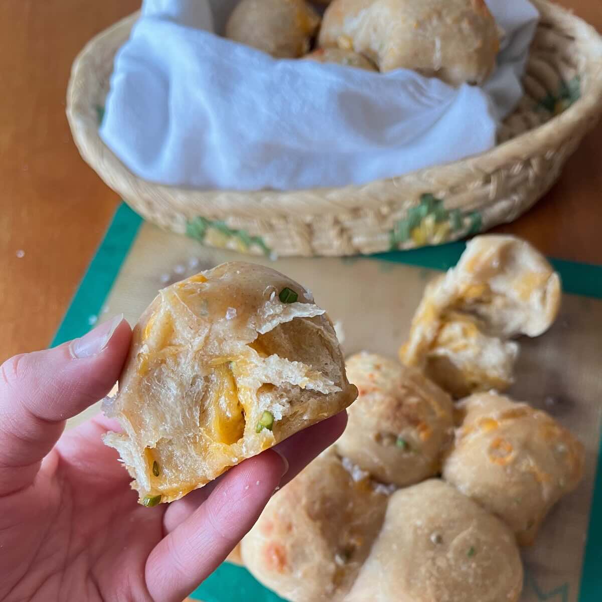 hand holding garlic scape cheddar sourdough rolls.