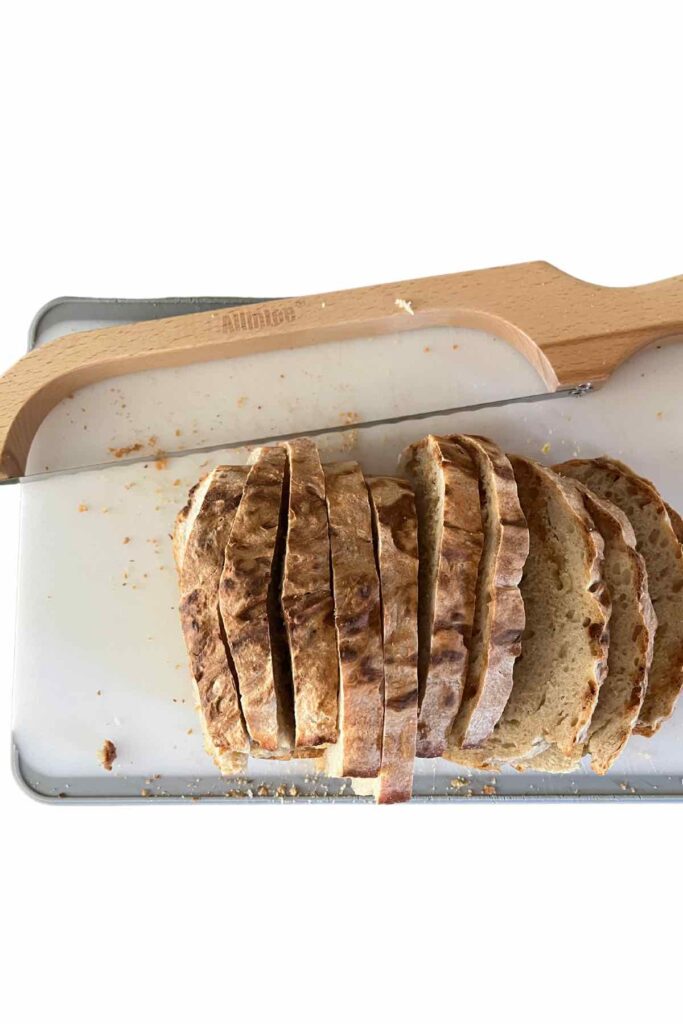 sliced bread on a cutting board with a bread knife on top.