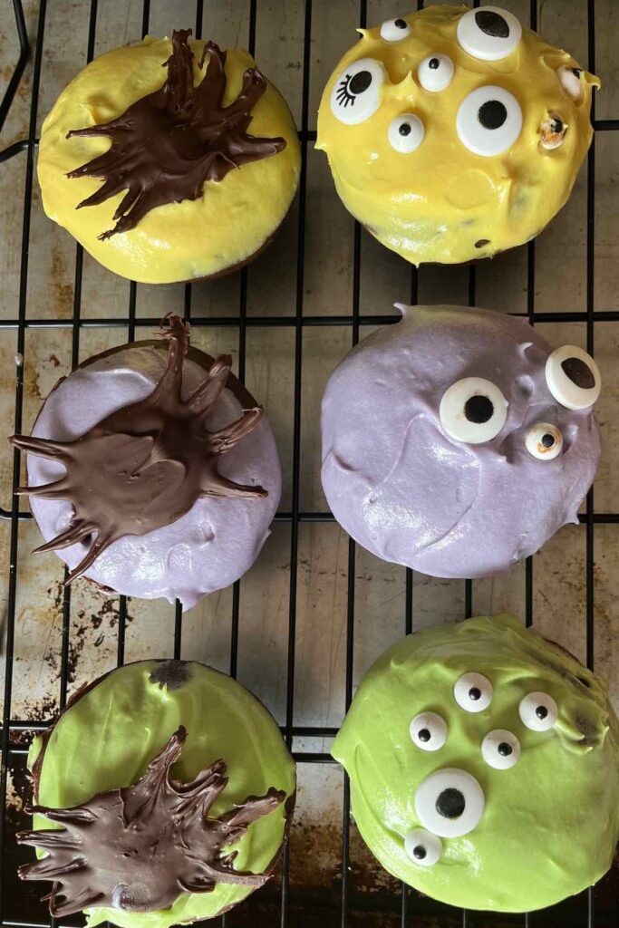 six monster donuts with edible eyes and chocolate spiders