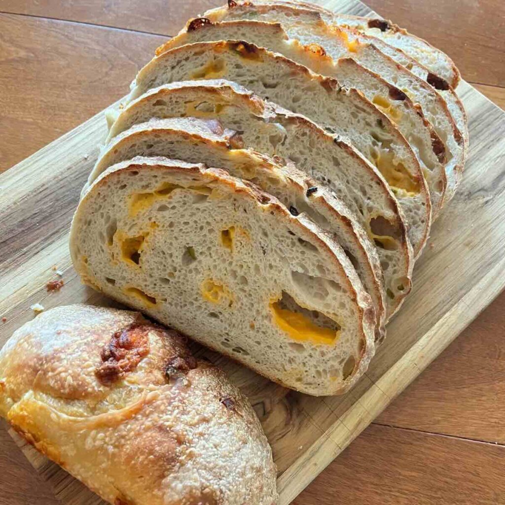sliced jalapeno cheddar bread on wooden cutting board.