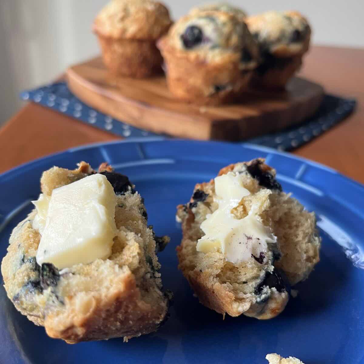 sourdough blueberry muffins with butter on a blue plate.