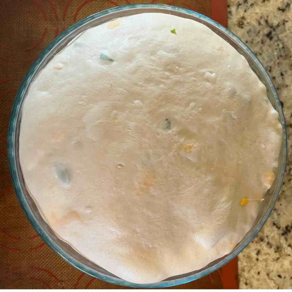 sourdough bread in a glass bowl with jalapeños and cheddar cheese.