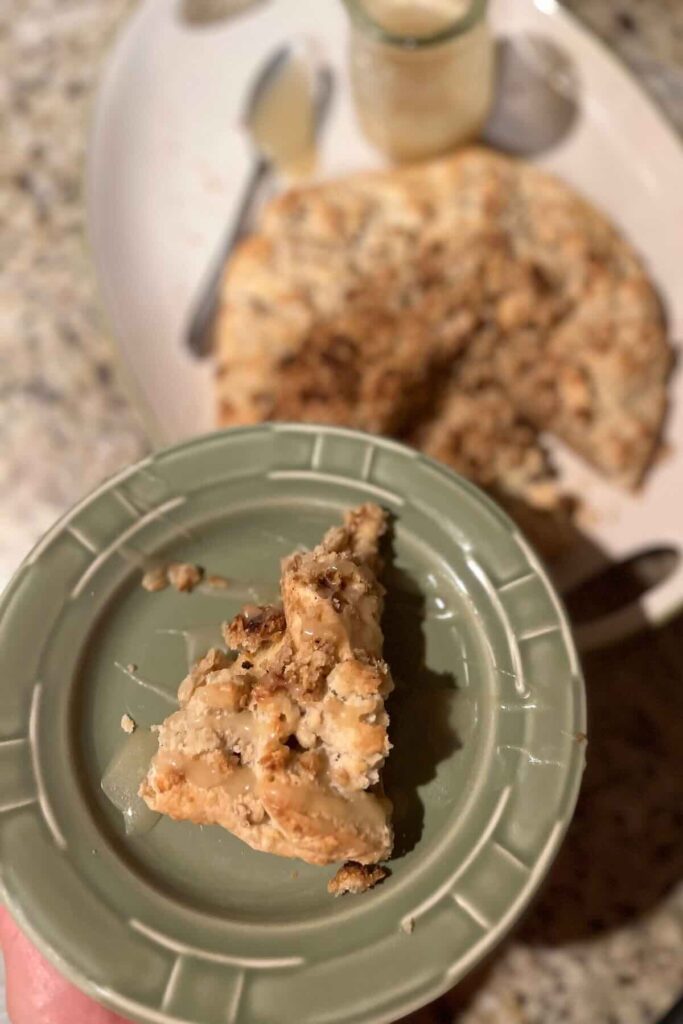 slice of apple crumble on a green plate with galette behind it.