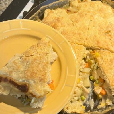 slice of chicken pot pie with sourdough pie crust on yellow plate.