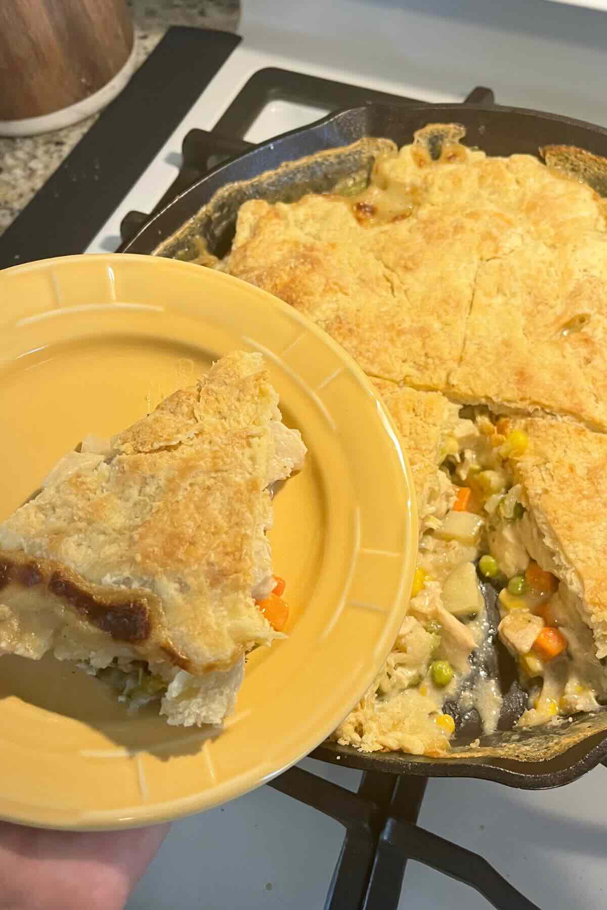 slice of chicken pot pie with sourdough pie crust on yellow plate.