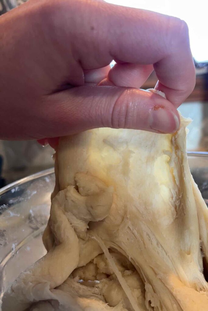 pulling dough with hand to see windowpane.