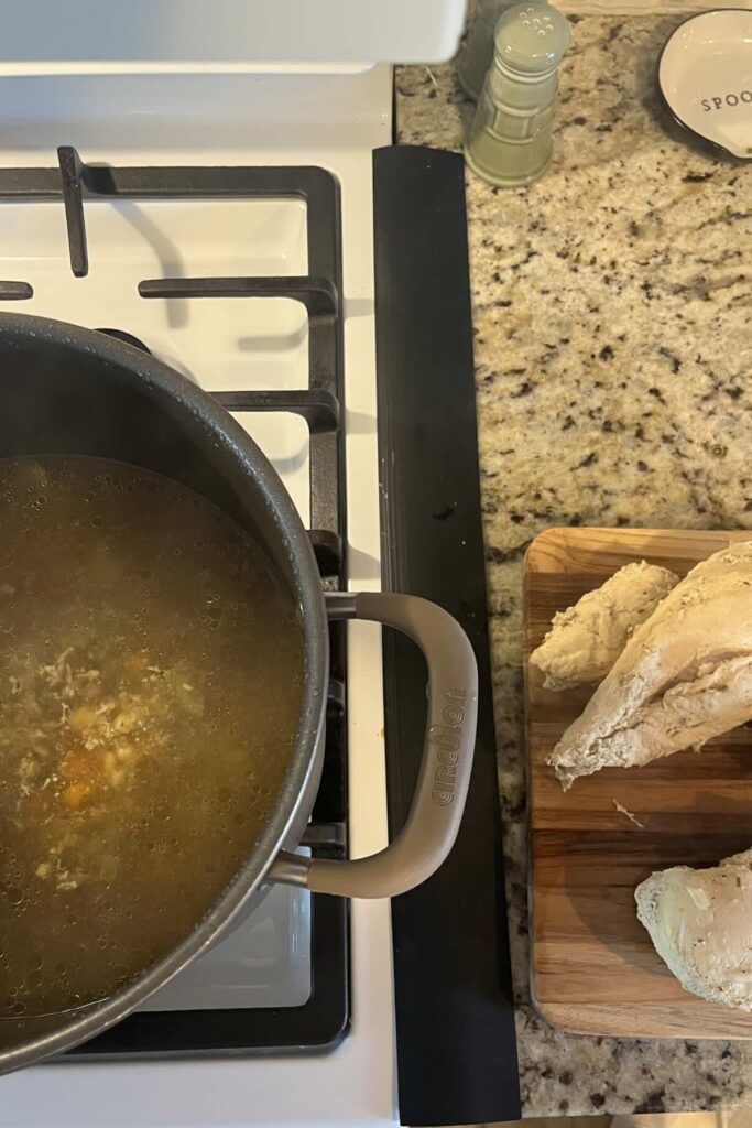 broth in pot and chicken on cutting board.