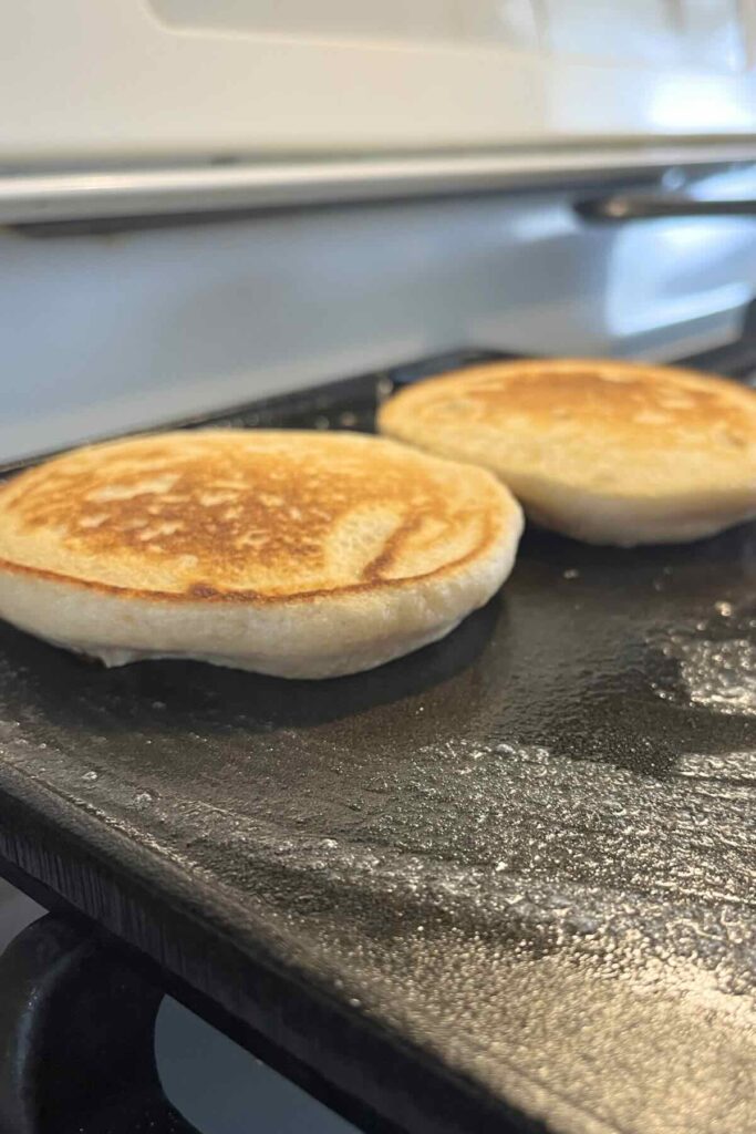two whole wheat pancakes on a griddle.