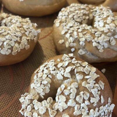 Honey oat sourdough bagels on baking sheet.