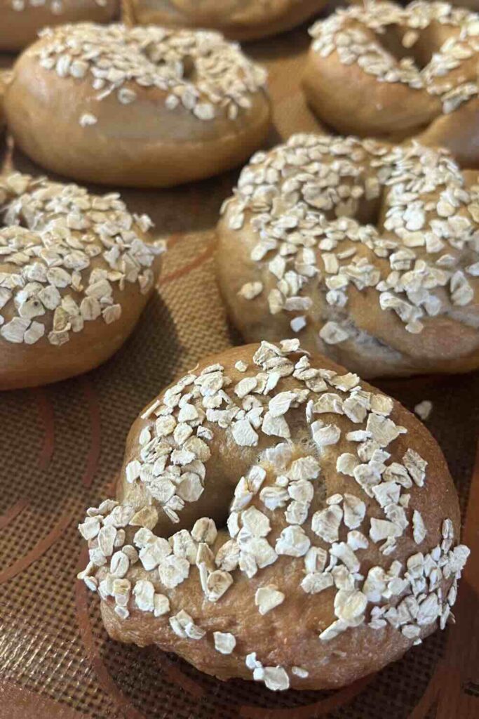 Honey oat sourdough bagels on baking sheet.